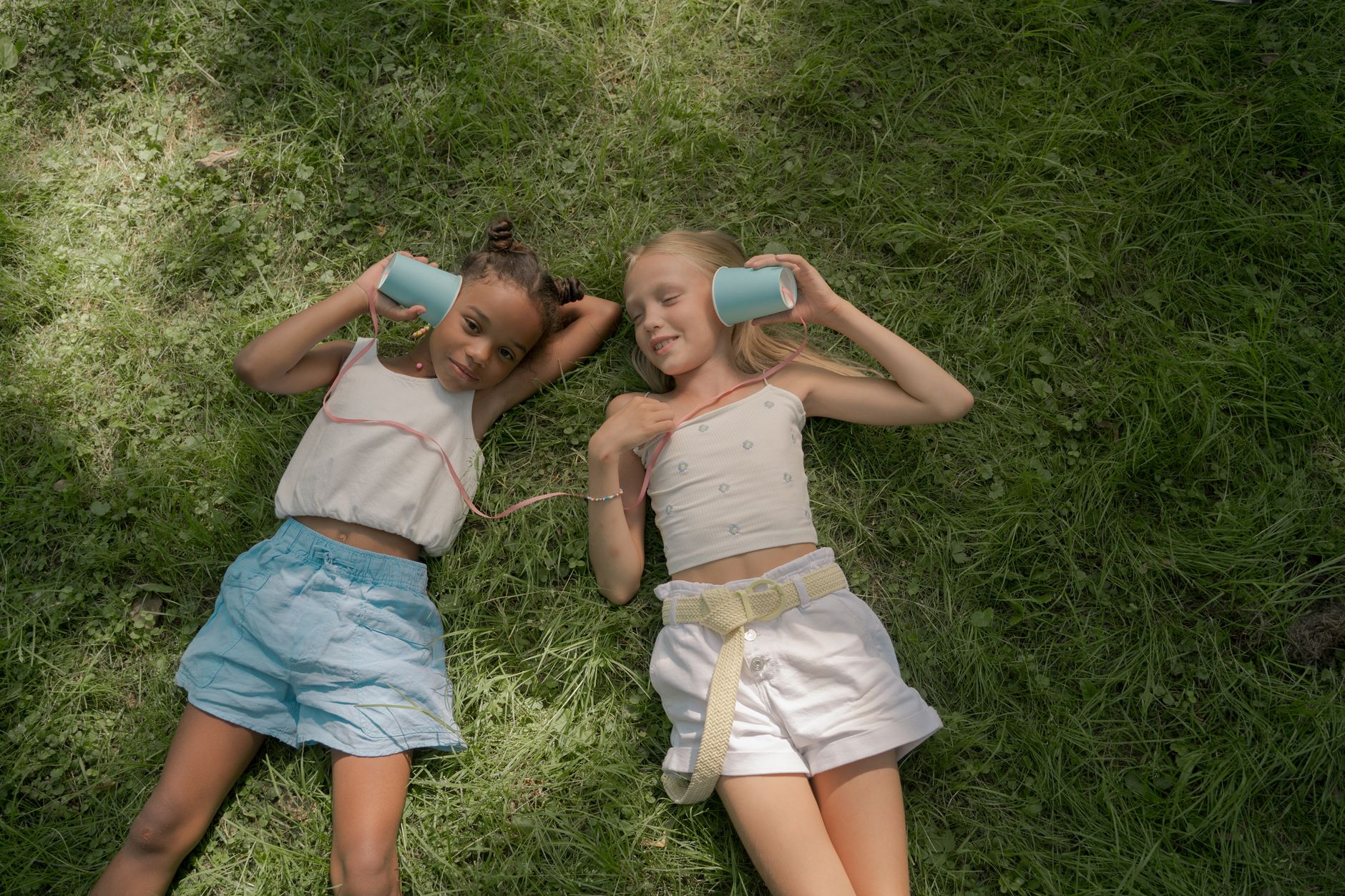 two girls laying on lawn and playing