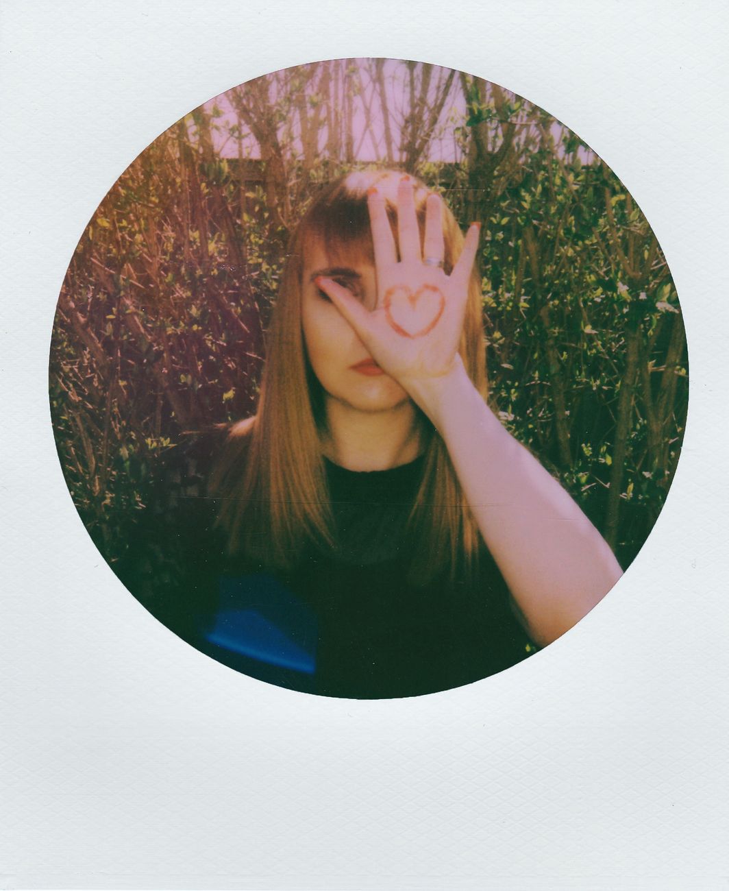 portrait of a young woman with a heart symbol painted on her hand