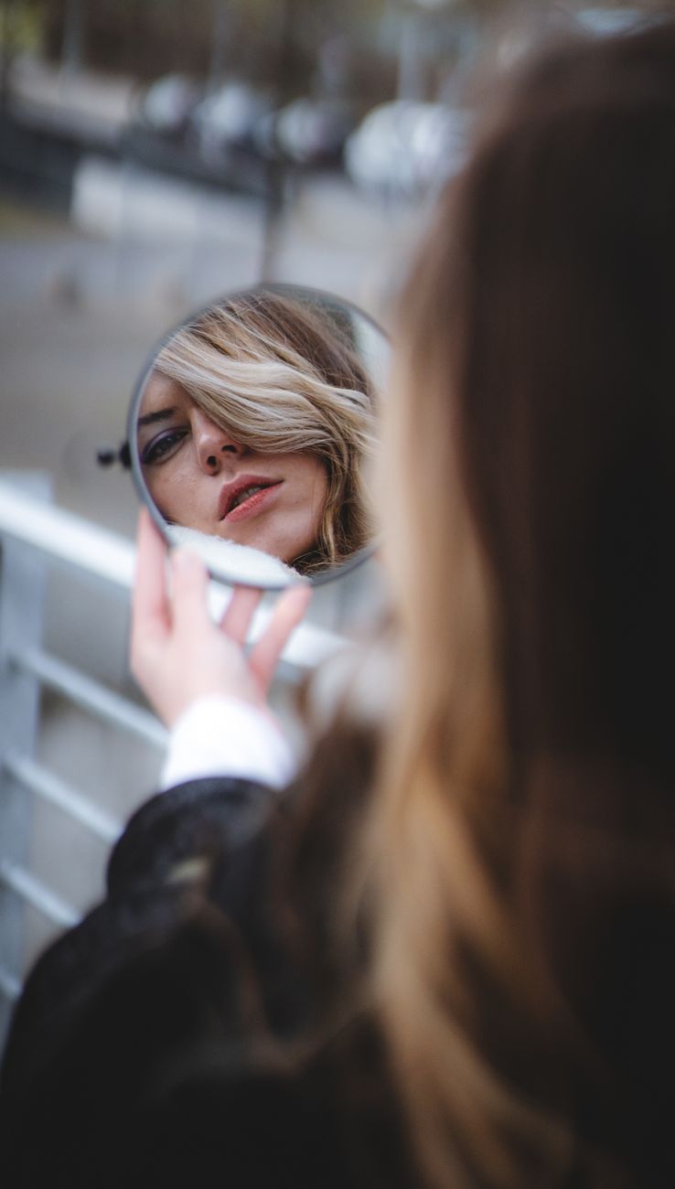 blonde woman reflecting in a round mirror