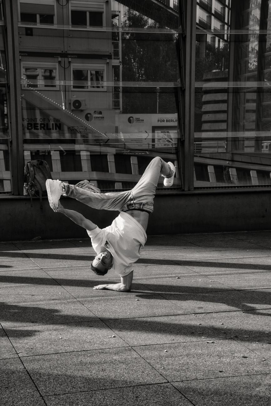 man in an acrobatic dance pose on the sidewalk