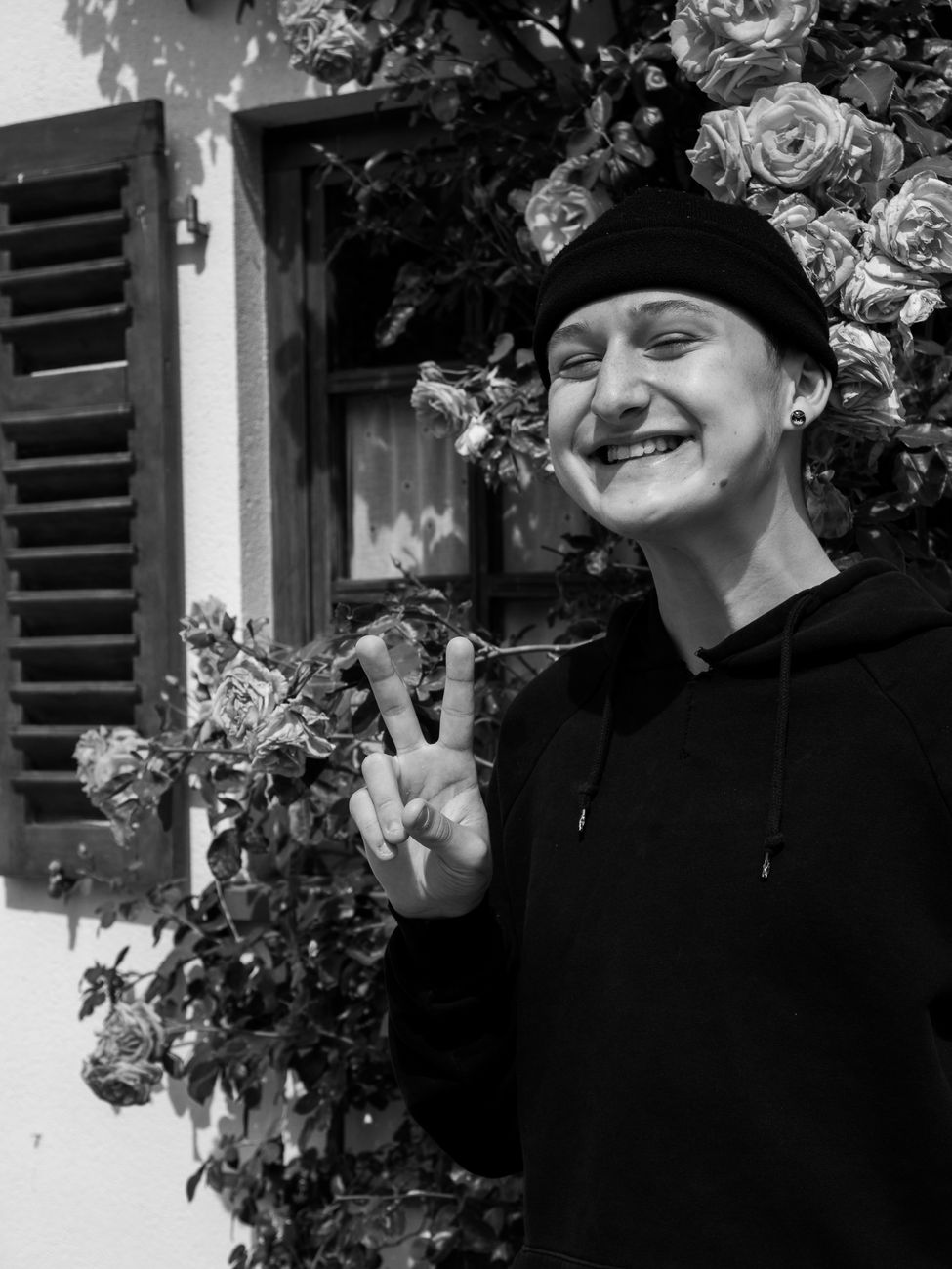 grayscale photo of a man in a hoodie smiling