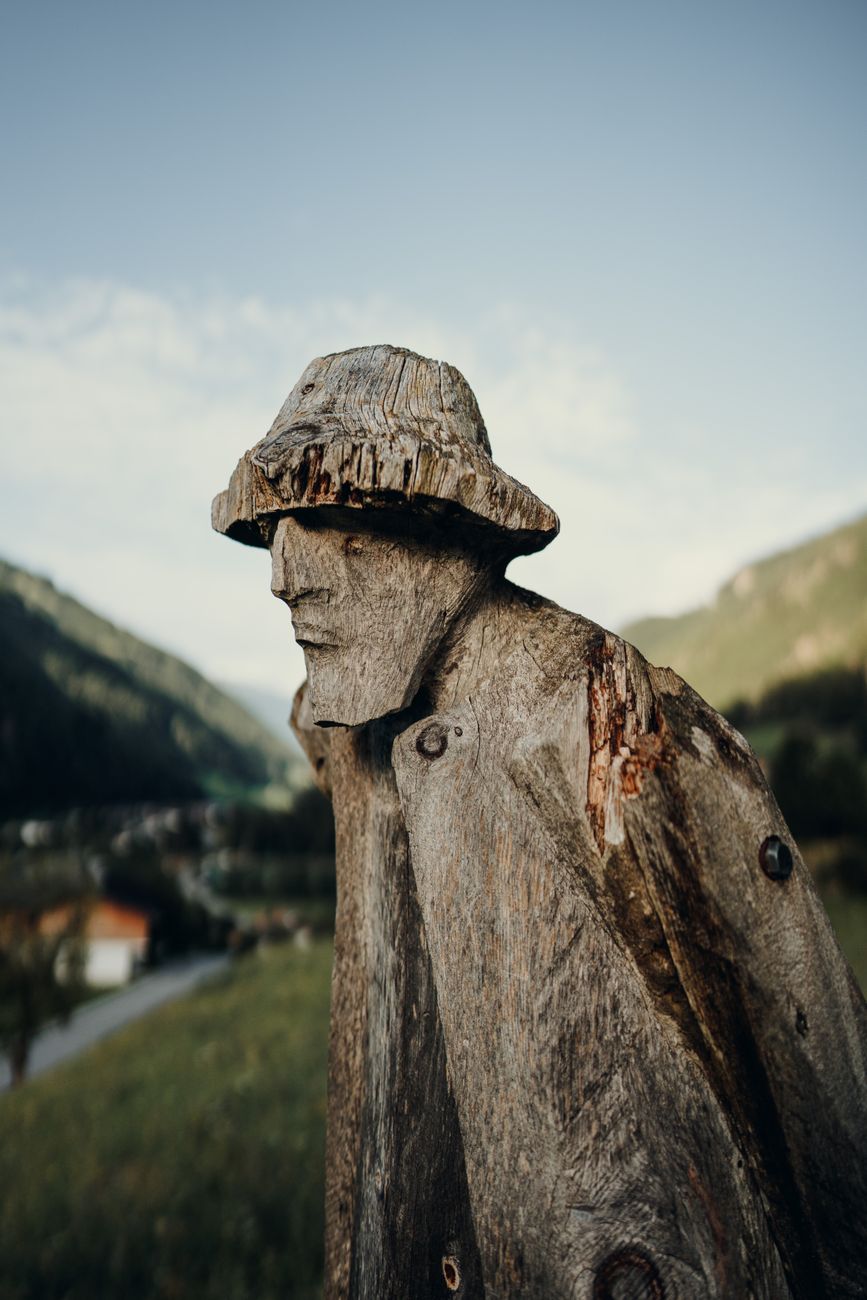 wooden sculpture of man with mountains in background