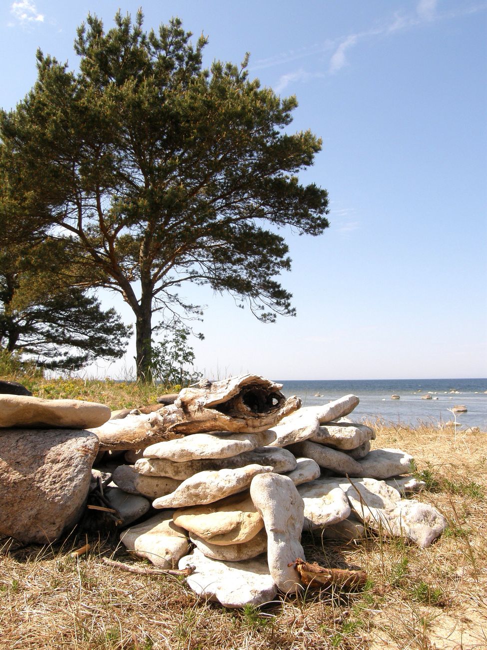 a pile of stones on the shore and sea in the background