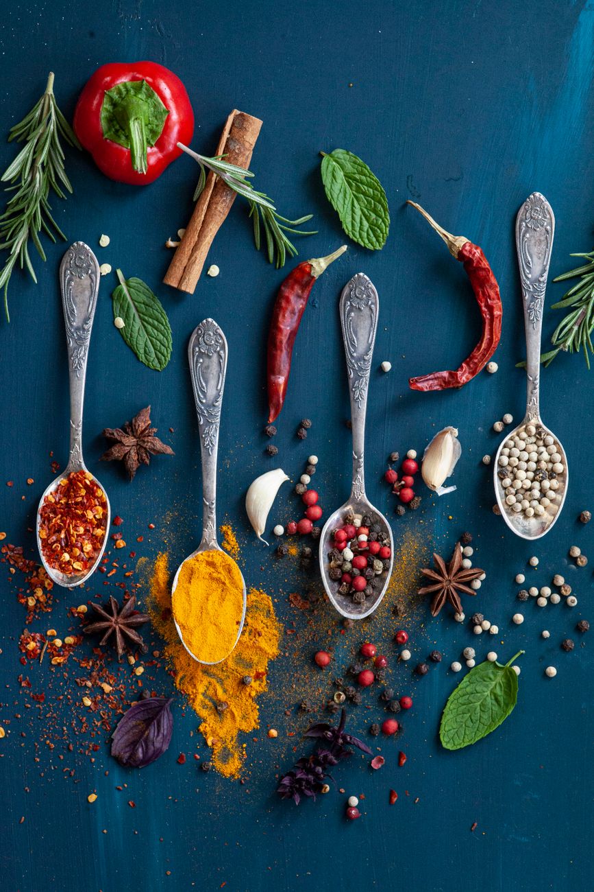 four spoons with spices on blue table