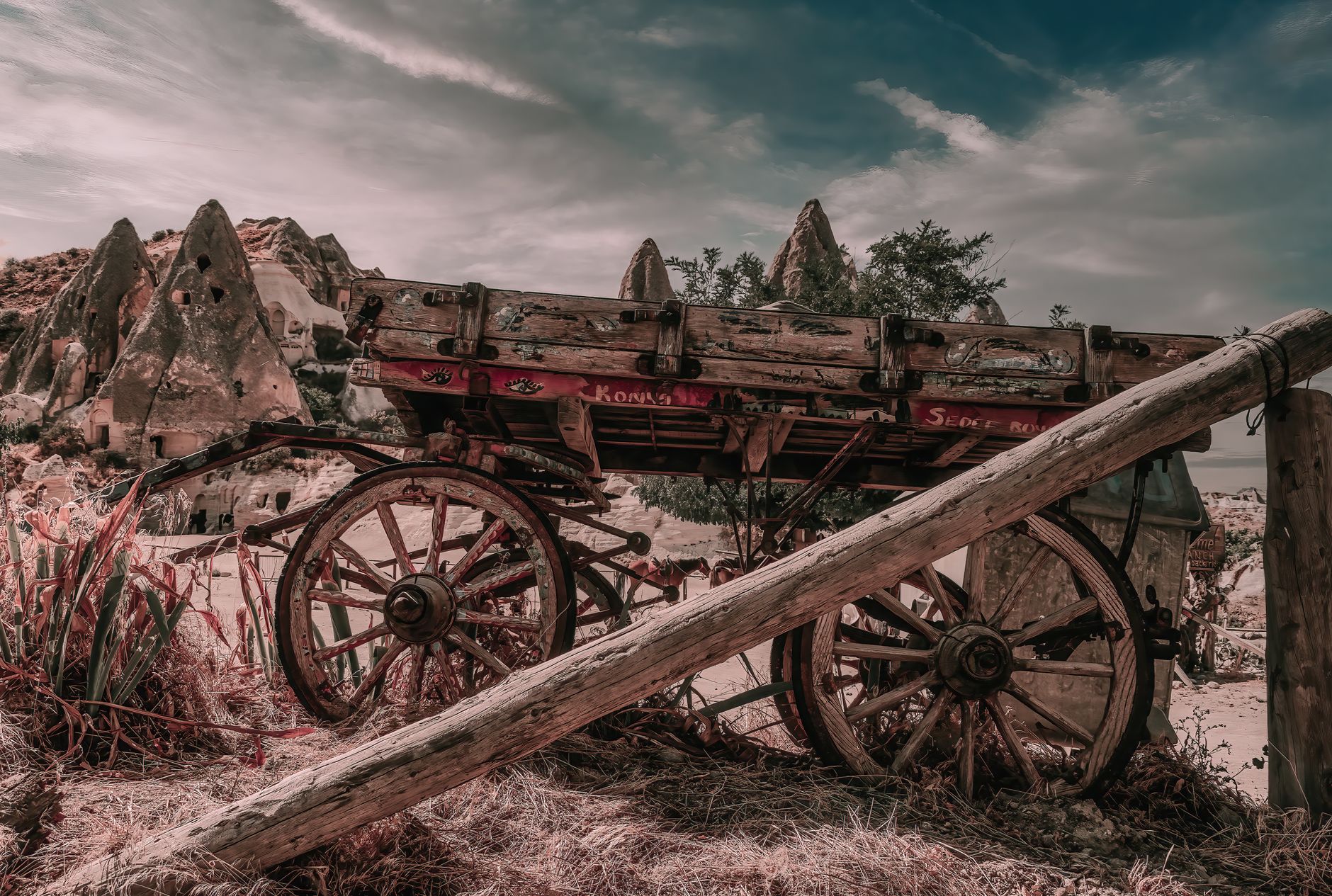 red and brown wooden cart on brown field under white clouds and blue sky