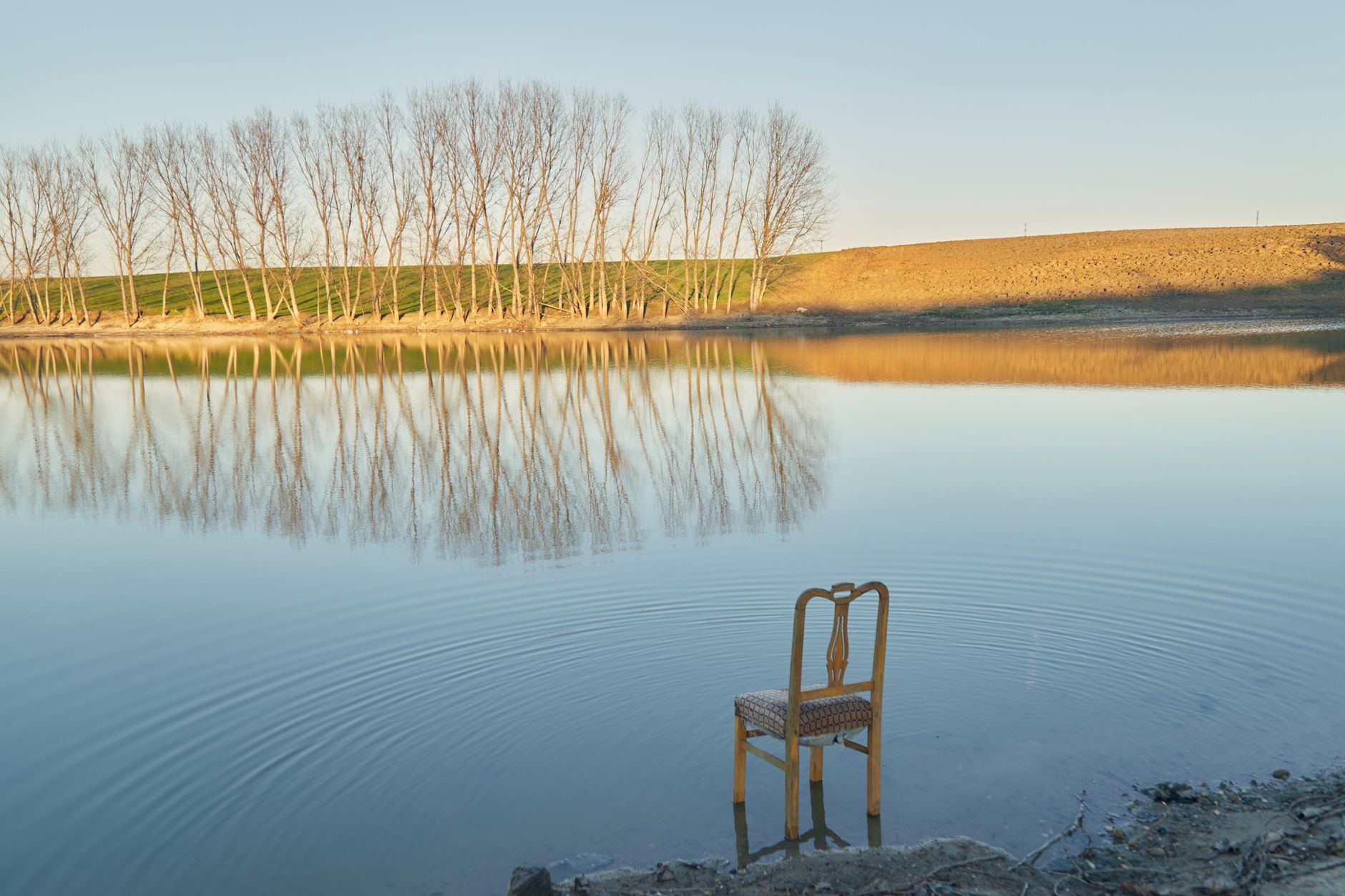 solitary chair by a tranquil lake at sunset