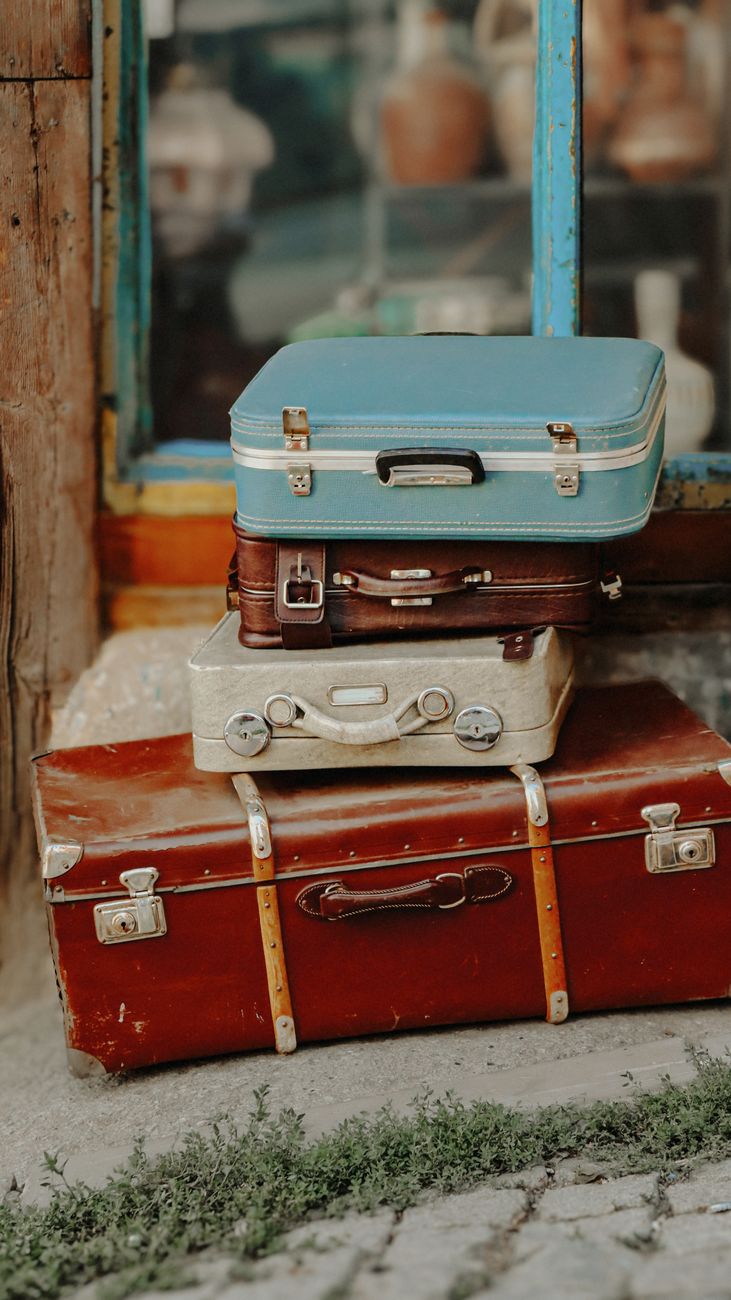vintage suitcases stacked outdoors near storefront