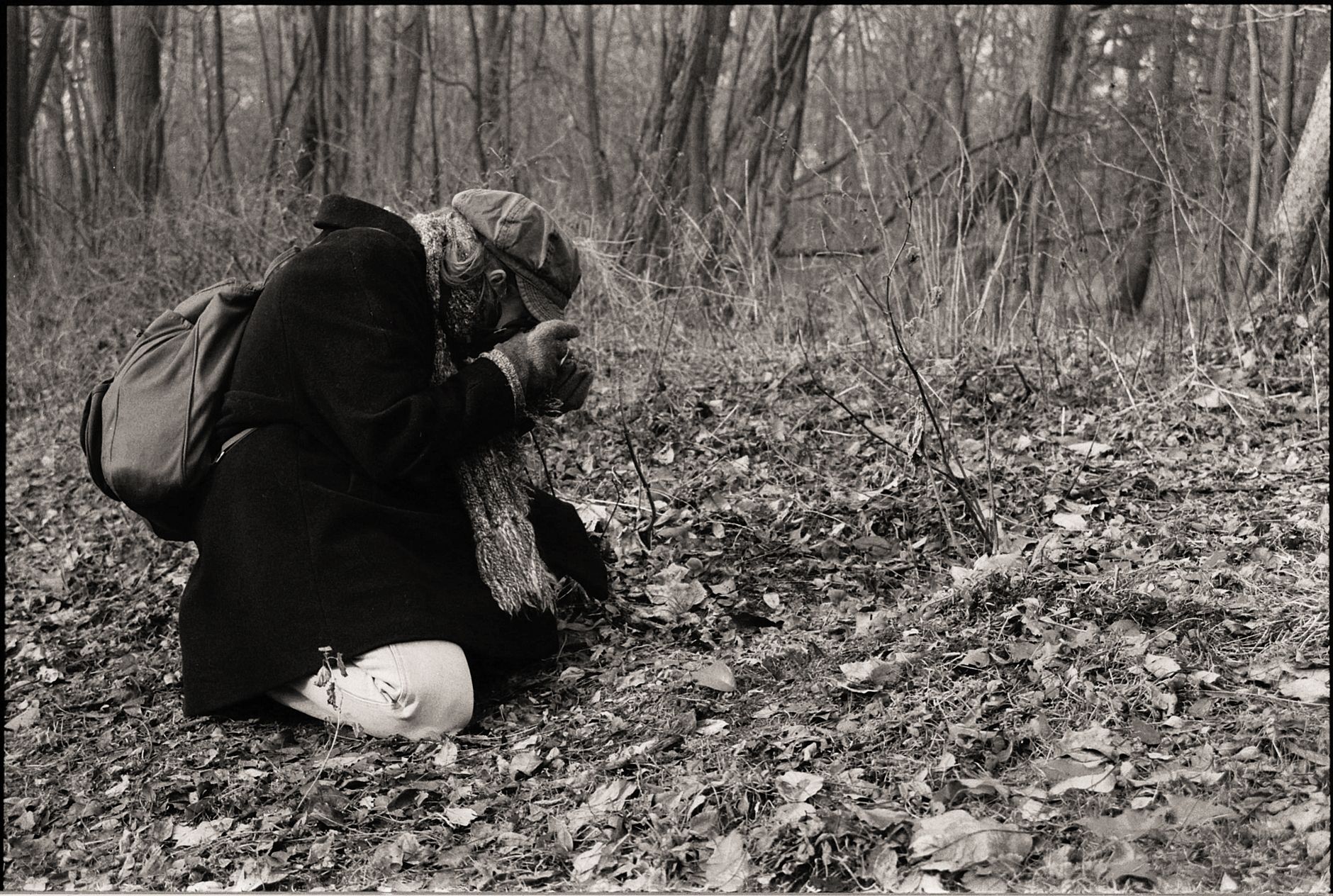 woman crouching and taking pictures of ground in forest