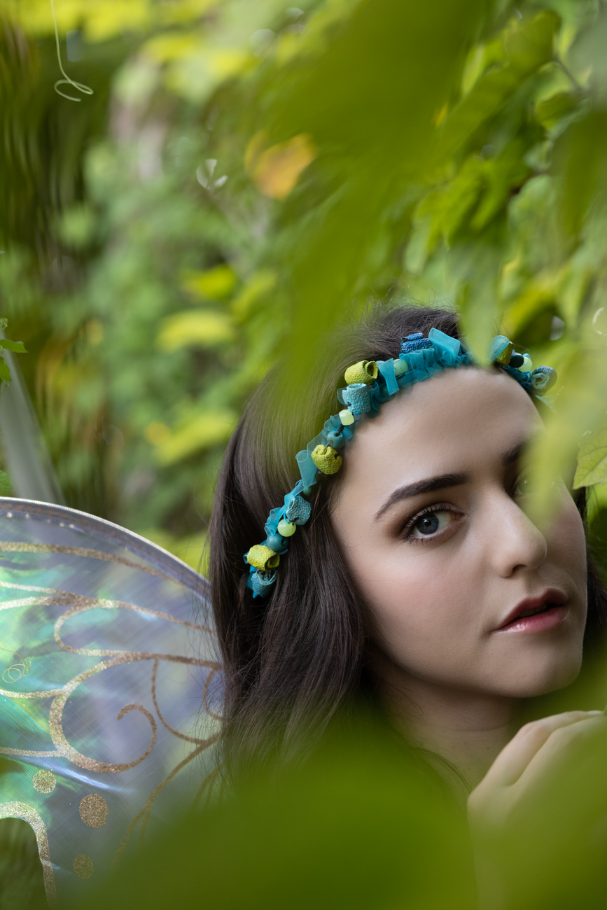 portrait of a young woman wearing a wreath and fairy wings
