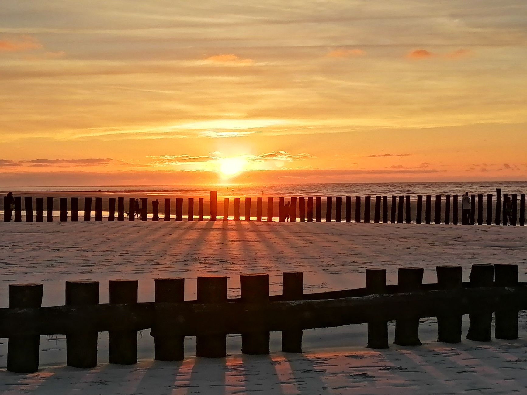 sunset at wangerooge beach with wooden breakwaters