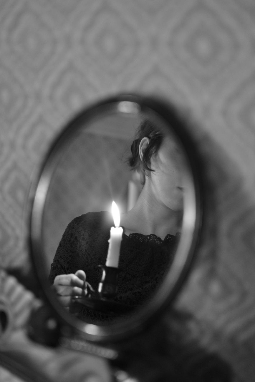 reflection of woman holding wax candle