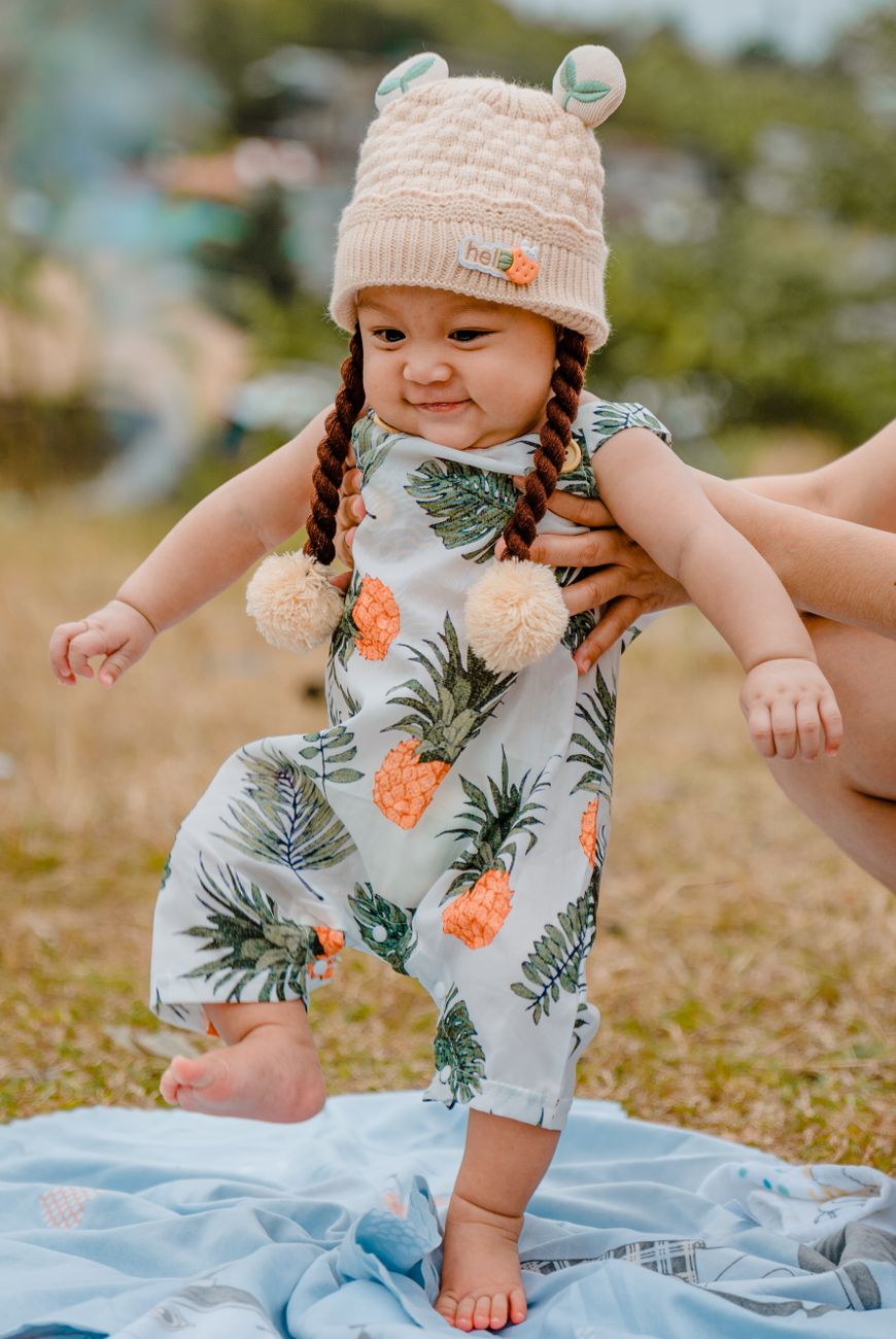 parent hands holding baby girl standing on blanket