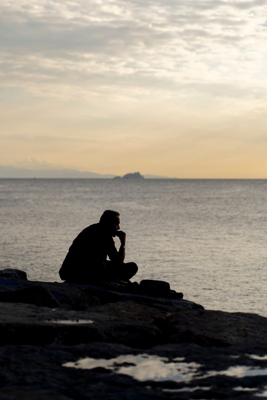 contemplative silhouette by the sea at sunset