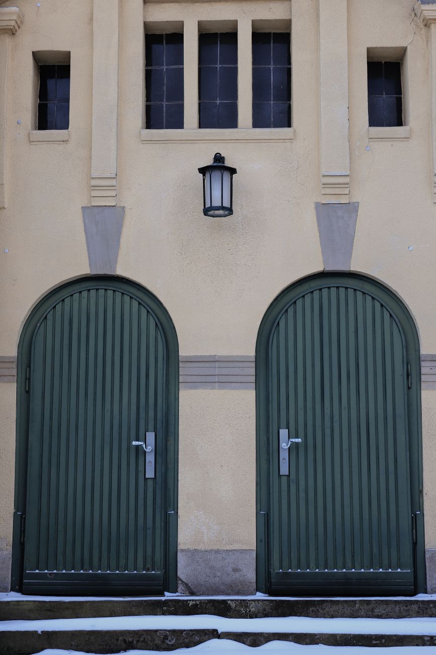 elegant entrance with green wooden arched doors