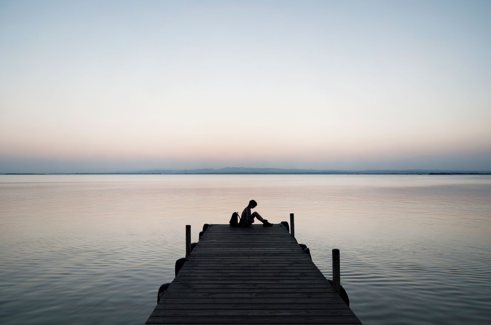 person sitting on wooden dock